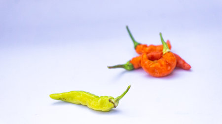 The ghost chilies (Naga Marica) focused on a green one with a white background.の写真素材