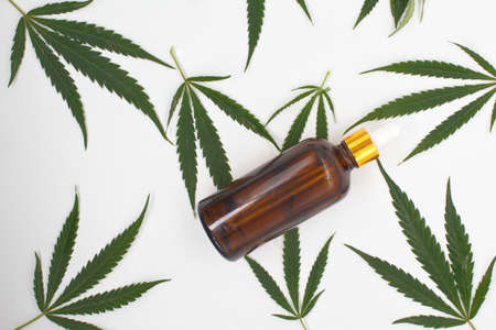 A bottle of cannabis CBD or hemp oil on marijuana leaf Alternative medicine concept. Cosmetics and skin care productsの写真素材
