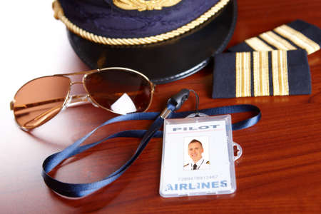 Professional airline pilot hat and id holder with epaulets and sun glasses laying on tableの写真素材