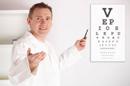 Male oculist doctor examining patient with an eye chart behind him. の写真素材
