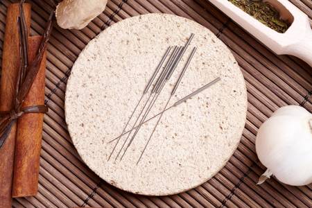 Acupuncture needles laying on the stone mat and herbs like garlic. TCM Traditional Chinese Medicine concept photoの写真素材