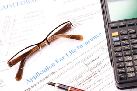 Life insurance application form with fountain pen, glasses and calculatorの写真素材