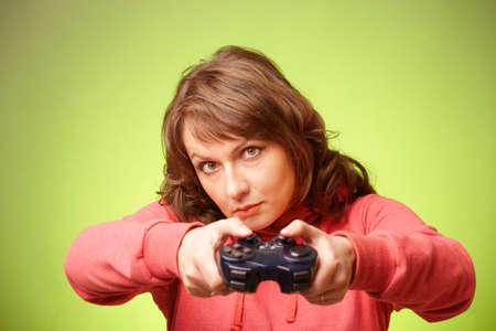 Beautiful womanl with gamepad playing vieogame over green background  Focus on face