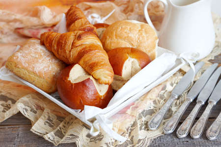 Various types of bread like French croissants, Italian ciabatta, German buns and other with silver knivesの写真素材