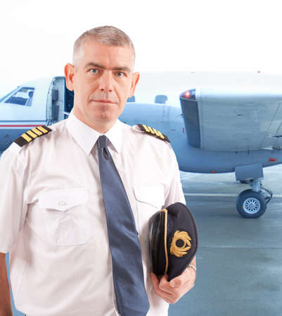 Airline pilot wearing uniform with epaulettes with passenger aircraft in backgroundの写真素材