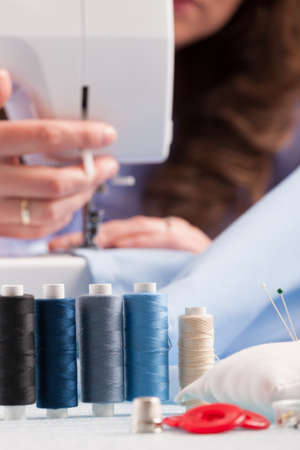 reels of colour threads and other sewing accessories like pins, buttons and thimble with woman