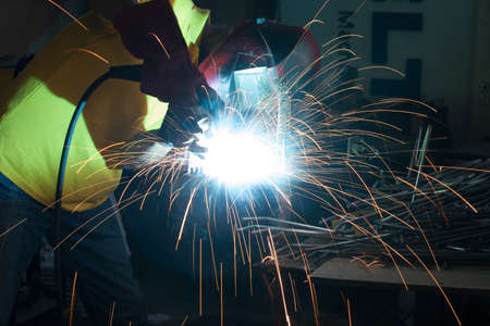 Man with protection mask welding metal with lots of sparks