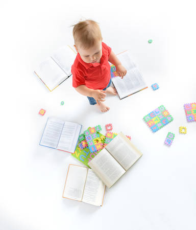 Little boy sitting among books and letter puzzlesの写真素材