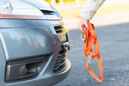 Hand holding tow rope near towing hook assembled to a broken carの写真素材