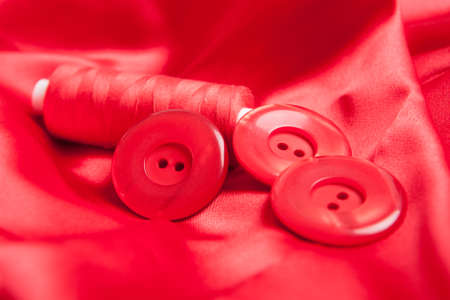 Red fabric satin with thread and buttons, sewing accesories の写真素材