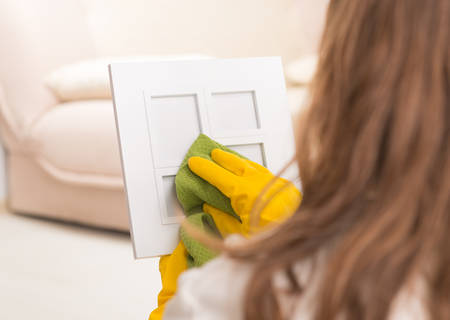 Woman cleaning frame in her home wearing yellow gloves and using clothの写真素材