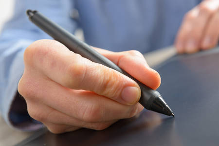 Male hands using graphics tablet at homeの写真素材