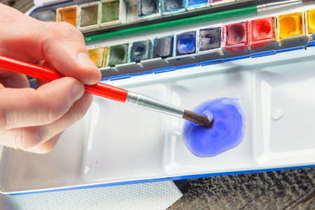 Hand of artist painting watercolor artwork