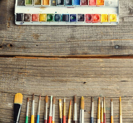 Professional watercolor aquarell paints in box with brushes on old wooden boardの写真素材