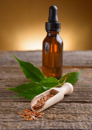 Dried linseed with macerated oil isolated on wooden tableの写真素材