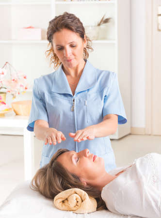 Professional Reiki healer doing reiki treatment to young womanの写真素材