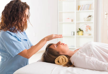 Professional Reiki healer doing reiki treatment to young womanの写真素材