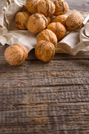 Pile of walnuts in paper bag on wooden boardの写真素材