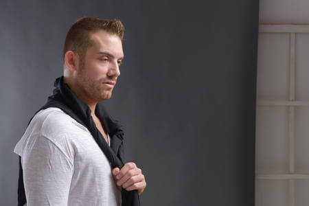 Cool looking man, wearing modern casual clothes posing over grey background