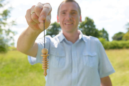 Man dowser using wooden pendulum, tool for dowsing の写真素材