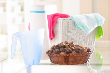 Basket full of soap nuts, natural bio detergent and laundry with bottle and scoop