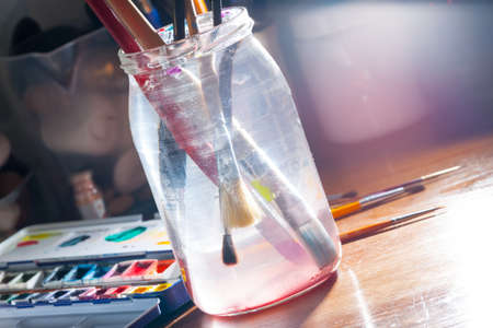 Brushes in jar with water and professional watercolor aquarell paints in box の写真素材