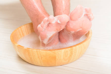 Male feet in a bowl with water and soap, hygiene and spa conceptの写真素材