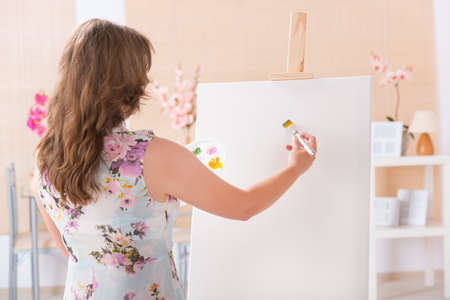 Beautiful woman painting on canvas at her home or workshopの写真素材