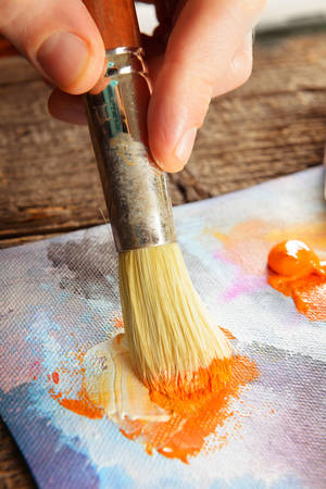 Artist hand with brush in acrylics paints on canvasの写真素材