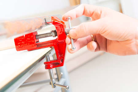 Hand using a vise to hold a rusty pipeの写真素材