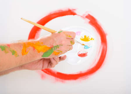 Hand holding paintbrush with artist palette, canvas on easel in a backgroundの写真素材