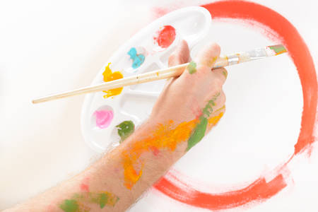 Hand holding paintbrush with artist palette, canvas on easel in a backgroundの写真素材