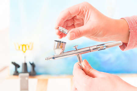 Hand holding a professional airbrush and opening cupの写真素材