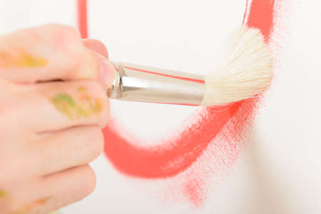 Hand holding paintbrush on canvasの写真素材