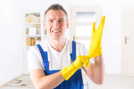 Smiling man cleaner wearing yellow gloves