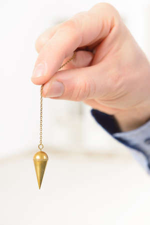 Hand with pendulum, tool for dowsing.の写真素材