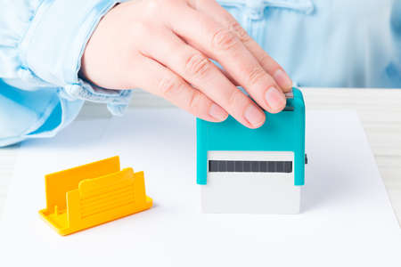Hand holding automatic stamp over blank paperの写真素材