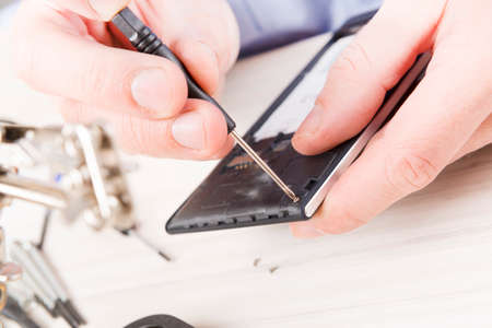 Serviceman repairing mobile phone in the electronic workshopの写真素材