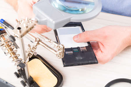 Serviceman repairing mobile phone in the electronic workshop