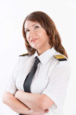 Beautiful woman pilot wearing uniform with epauletes, standing isolated on white background.の写真素材