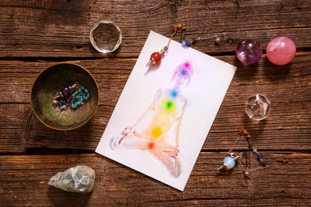 Chakras illustrated over human body with natural crystals and pendulum