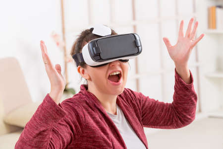 Happy woman using virtual reality headset at home