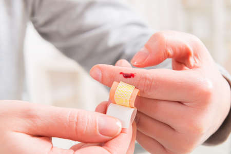 Applying adhesive bandage on bleeding finger