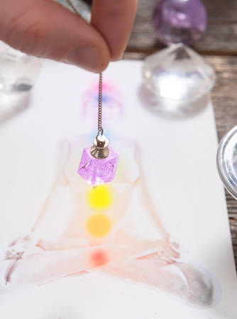 Chakras illustrated over human body with natural crystals and pendulum