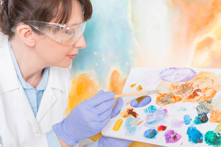 Artwork conservator at work with old painting wearing protective suitの写真素材