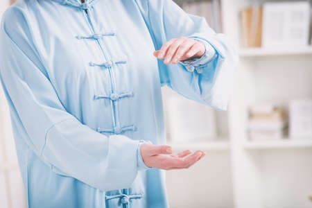 Beautiful woman doing qi gong tai chi exercise or reiki wearing professional, original Chinese clothes at homeの写真素材