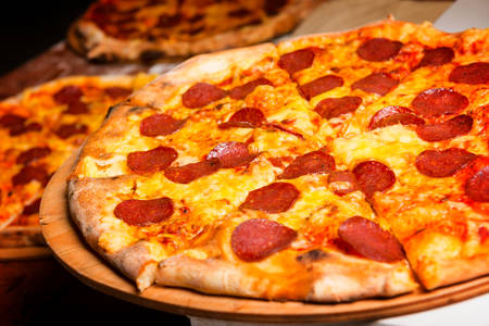 Fresh original Italian pizza on a wooden board in Italian pizzeriaの写真素材