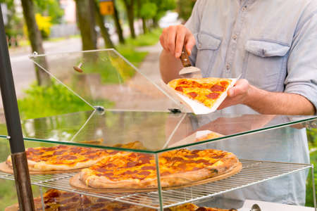 A street food vendor selling pizza by slice outdoors