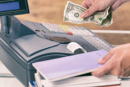 Seller using cash register at bookstore and holding moneyの写真素材