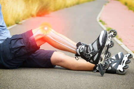 Injured skater sitting with his painful legの写真素材